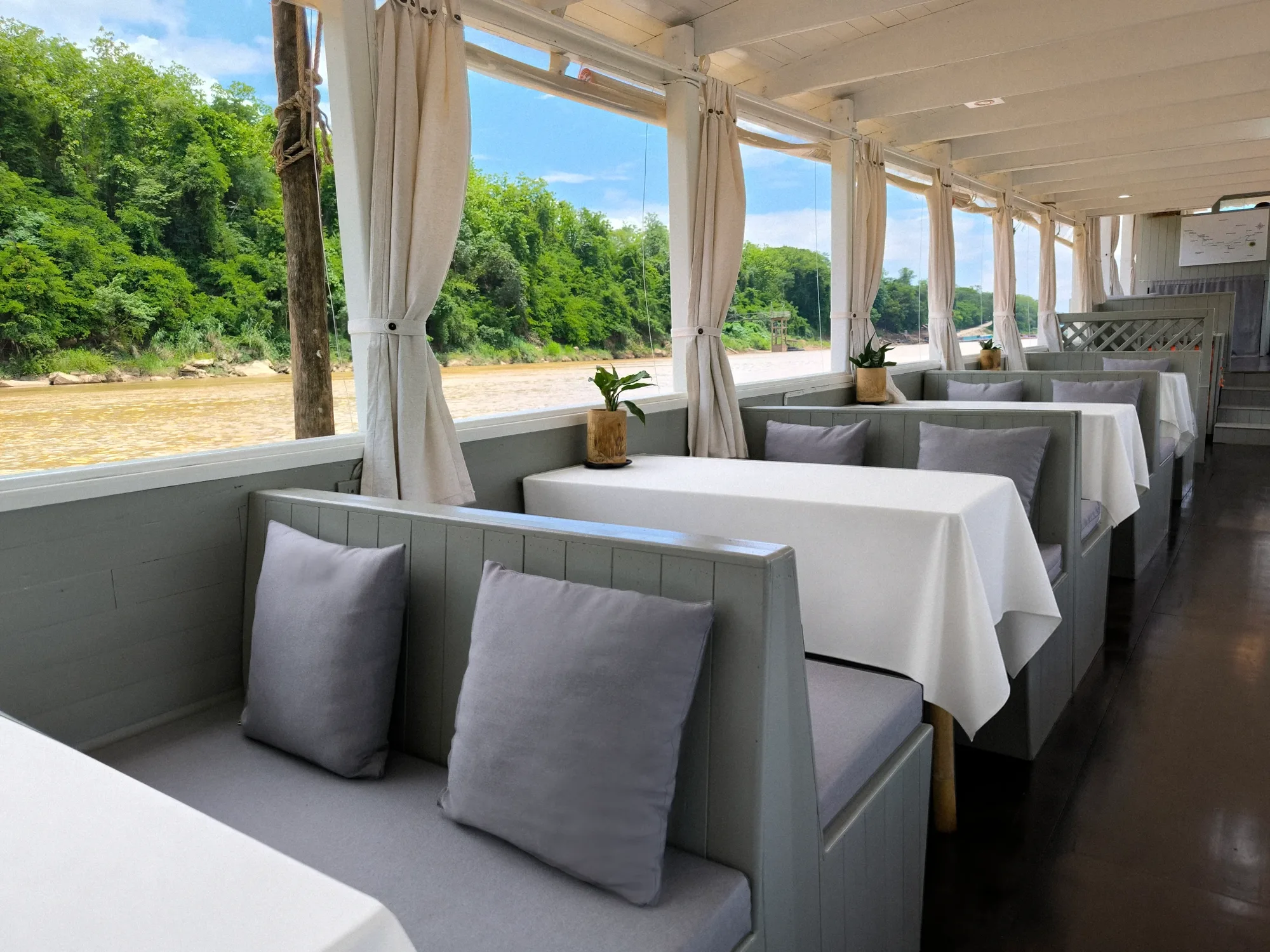 Cushioned benches and white-clothed tables along the deck of the Mekong Cruises boat