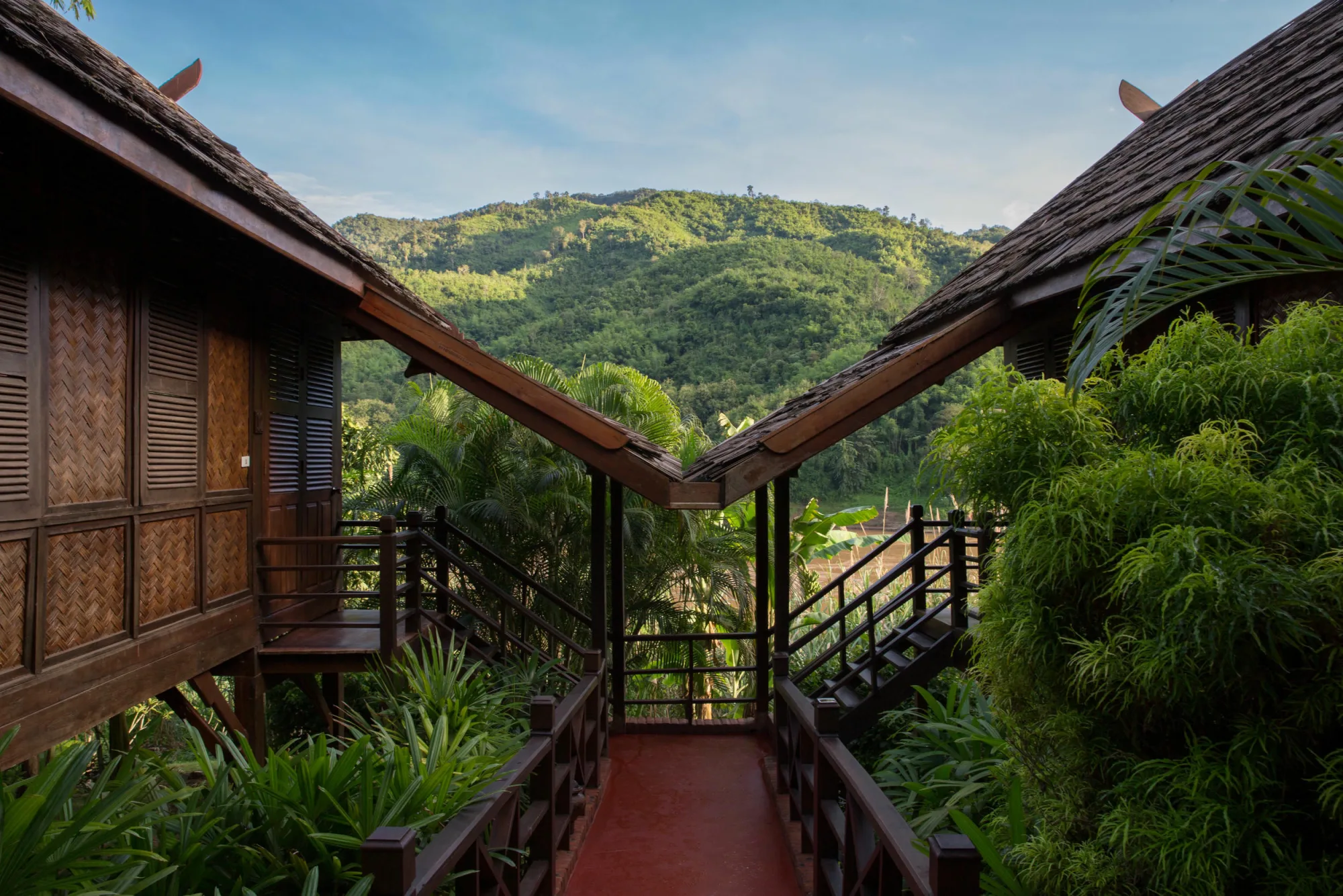 Walkway along the bungalows with a view of the forested hills across the river